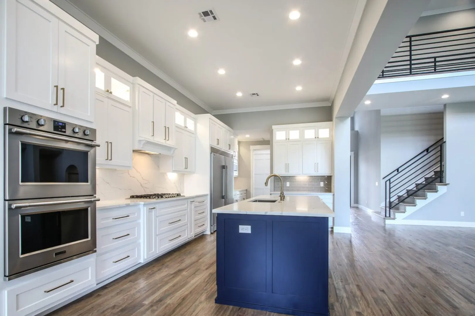 A kitchen with white cabinets and blue island.