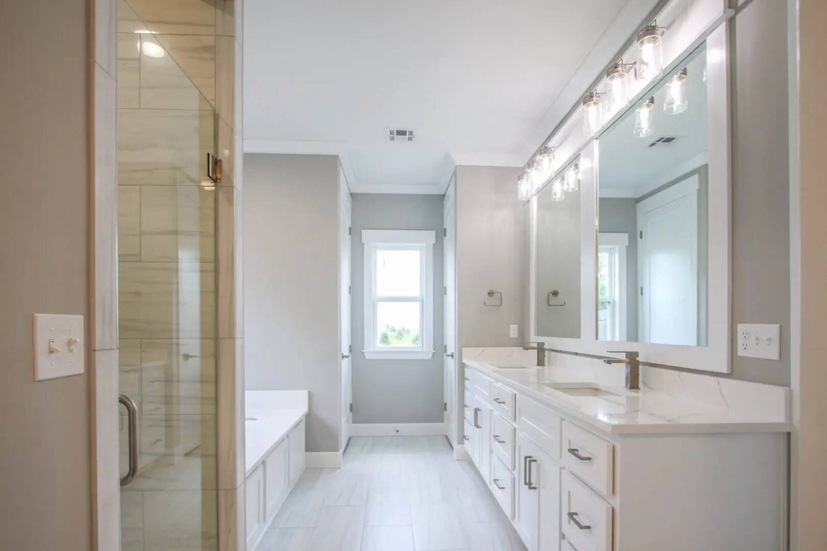 A bathroom with white cabinets and a large mirror.