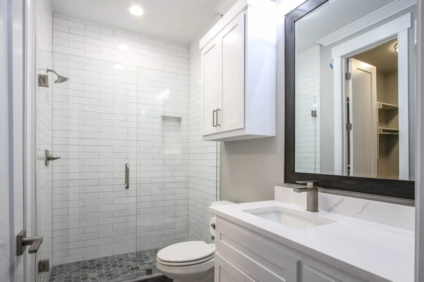 A bathroom with white cabinets and a toilet.