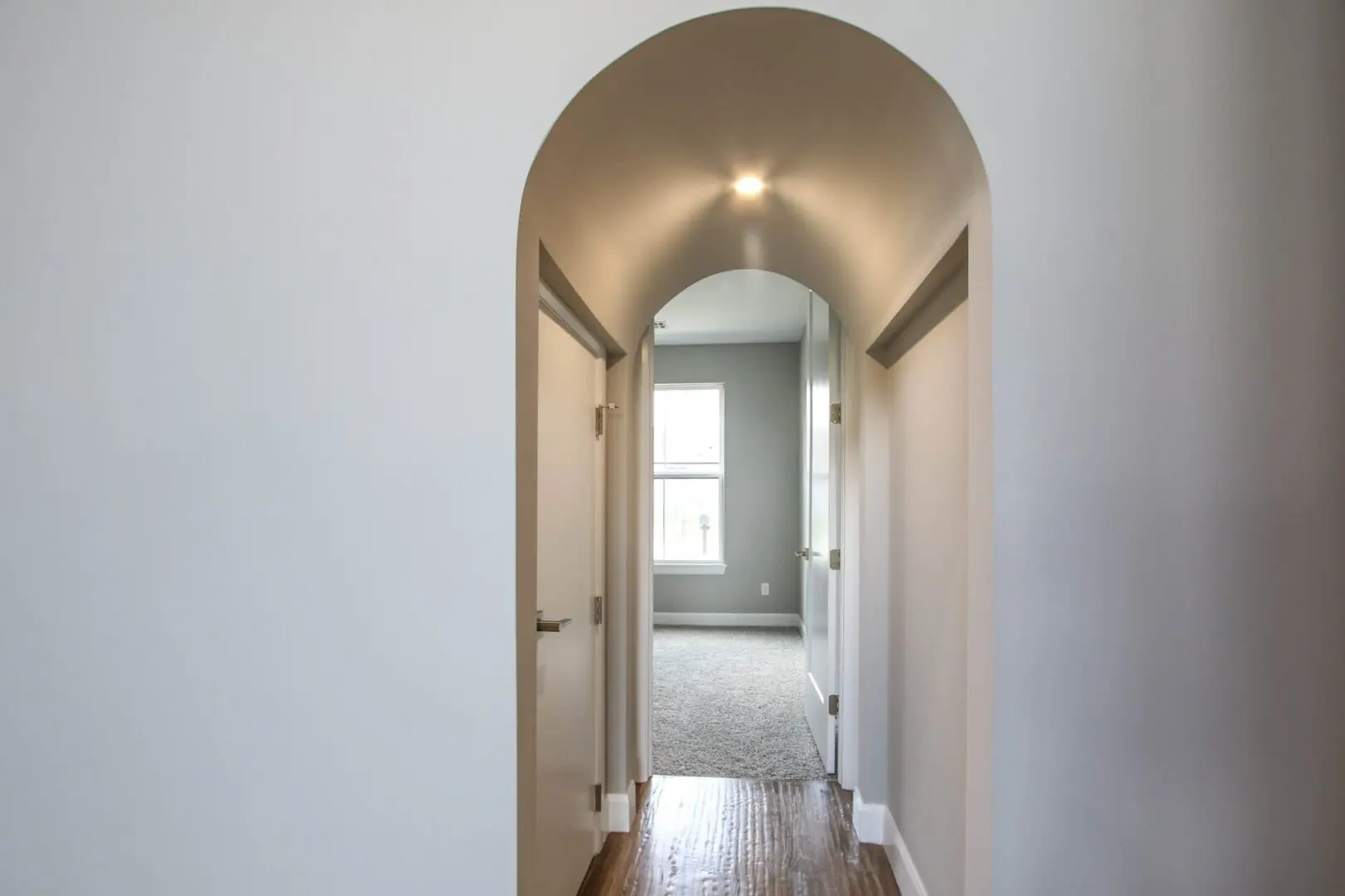 A hallway with a door open and a window in the background.