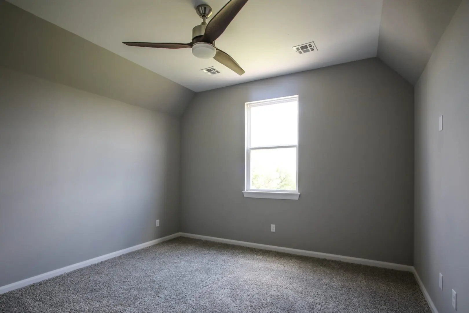 A bedroom with a ceiling fan and a window.