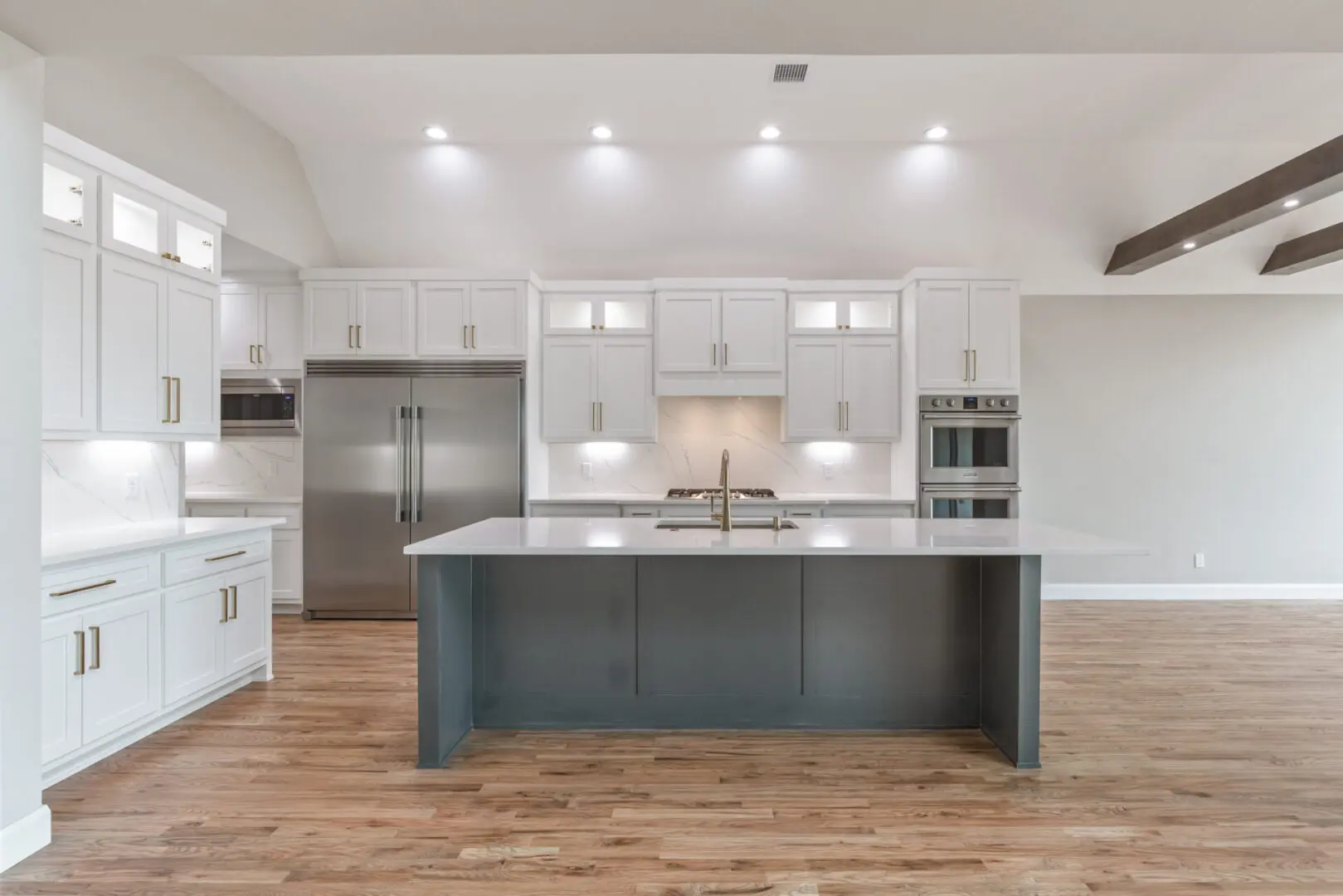 A kitchen with white cabinets and wood floors.