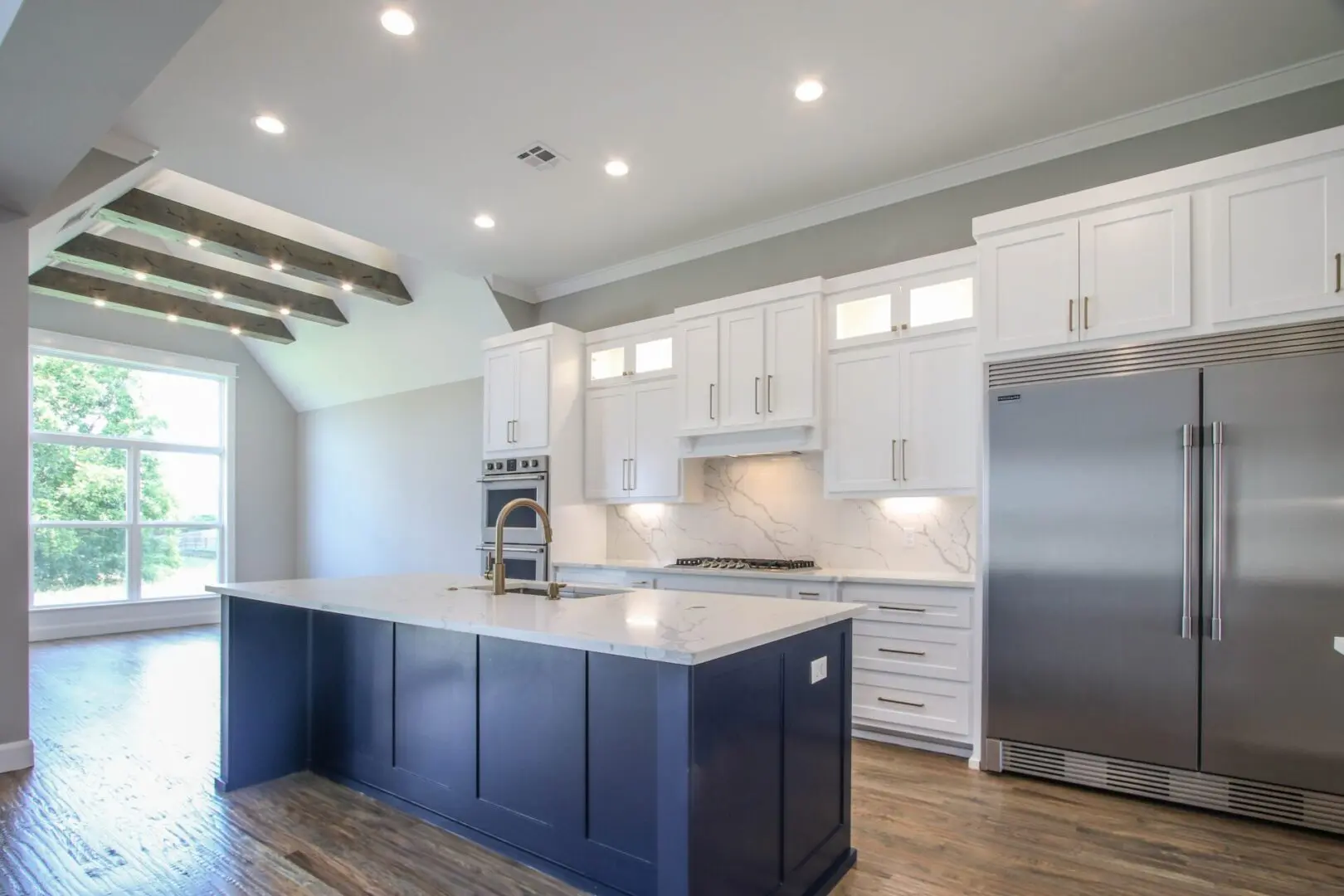 A kitchen with white cabinets and blue island.