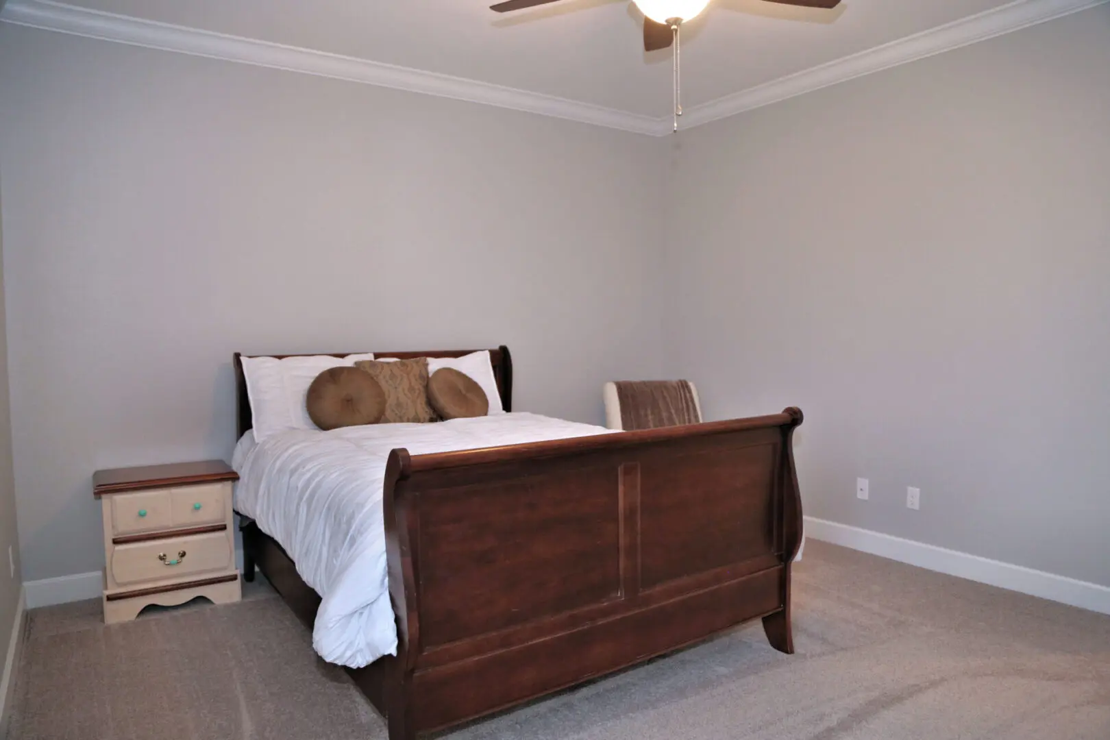 A bedroom with a bed, dresser and ceiling fan.