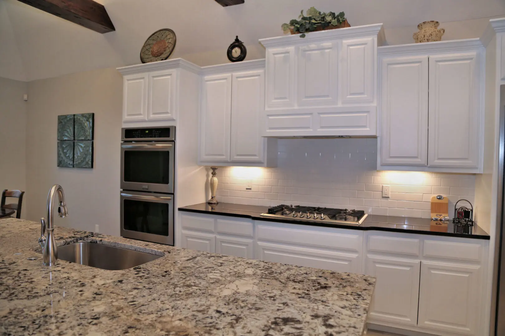 A kitchen with white cabinets and granite counter tops.