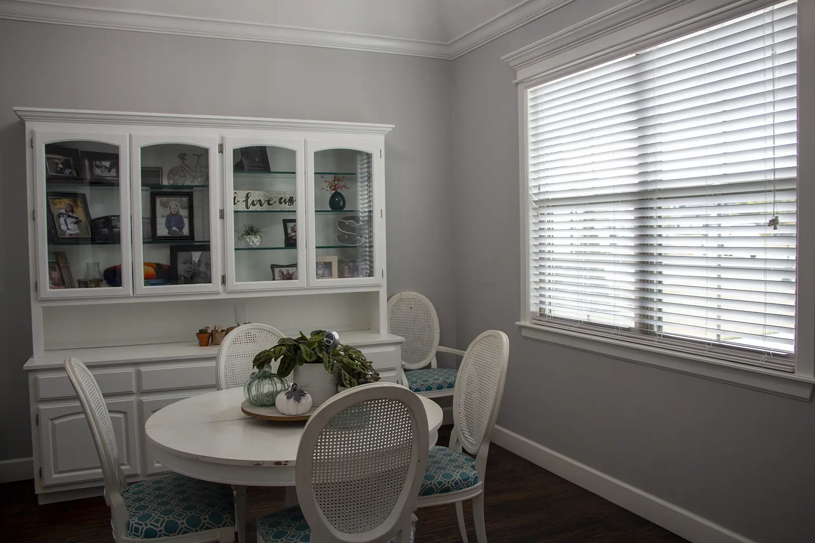 A dining room with white furniture and a window.