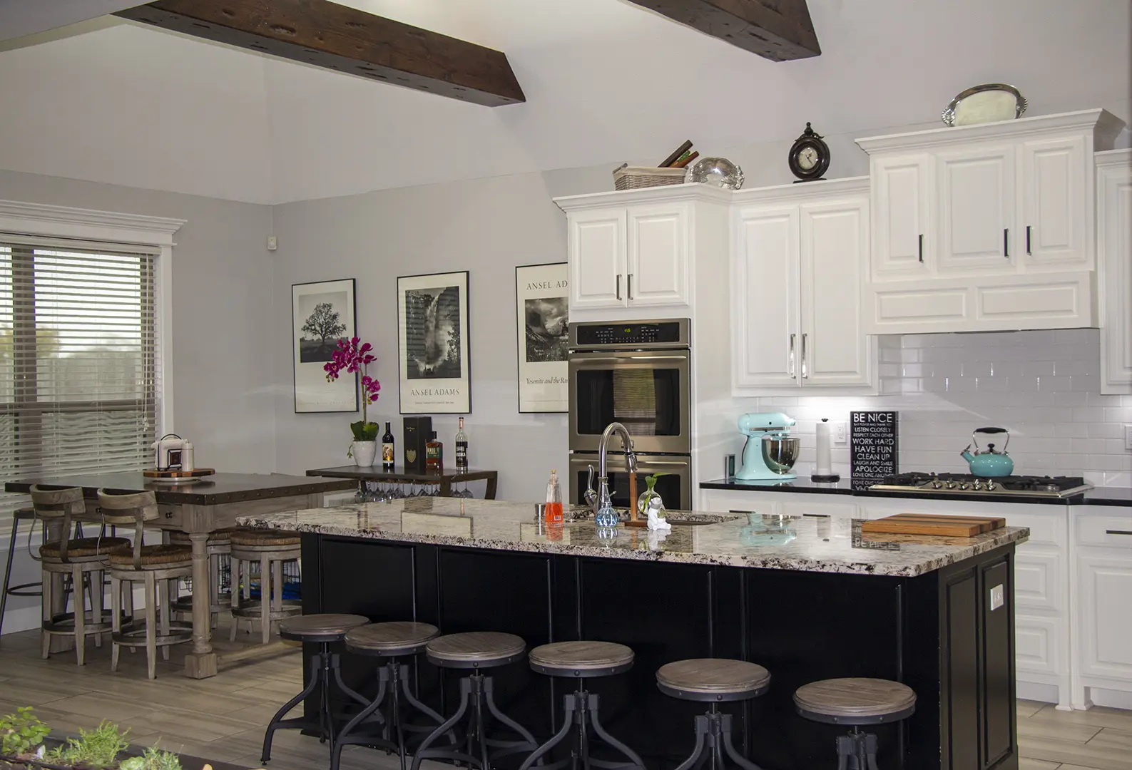 A kitchen with white cabinets and black island.