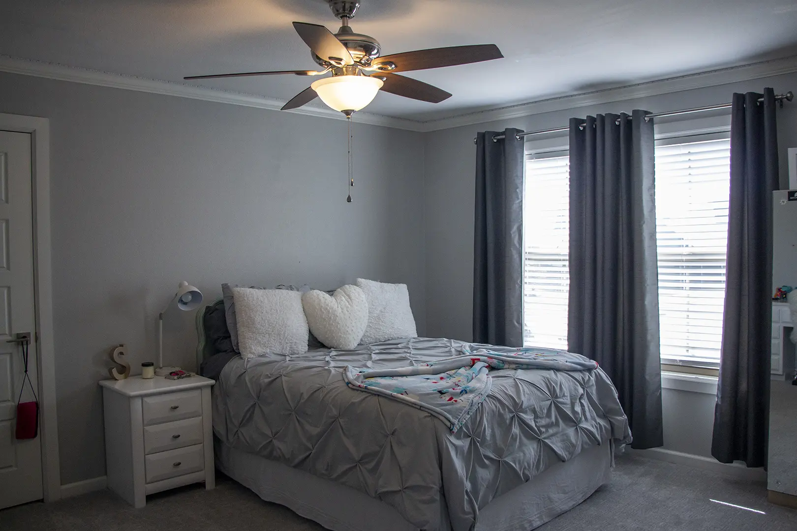 A bedroom with a bed, dresser and window.