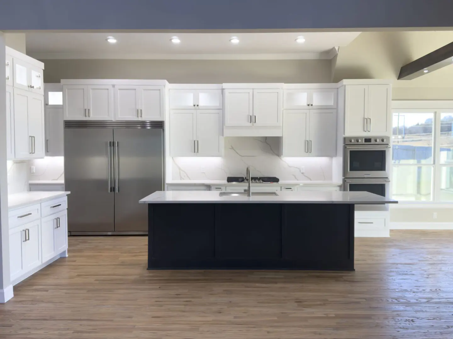 A kitchen with white cabinets and black island.