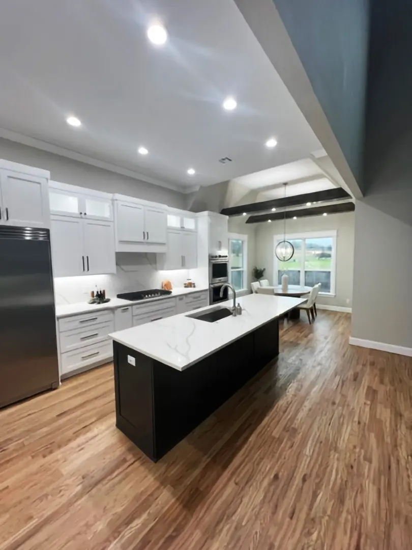 A kitchen with white cabinets and black island.