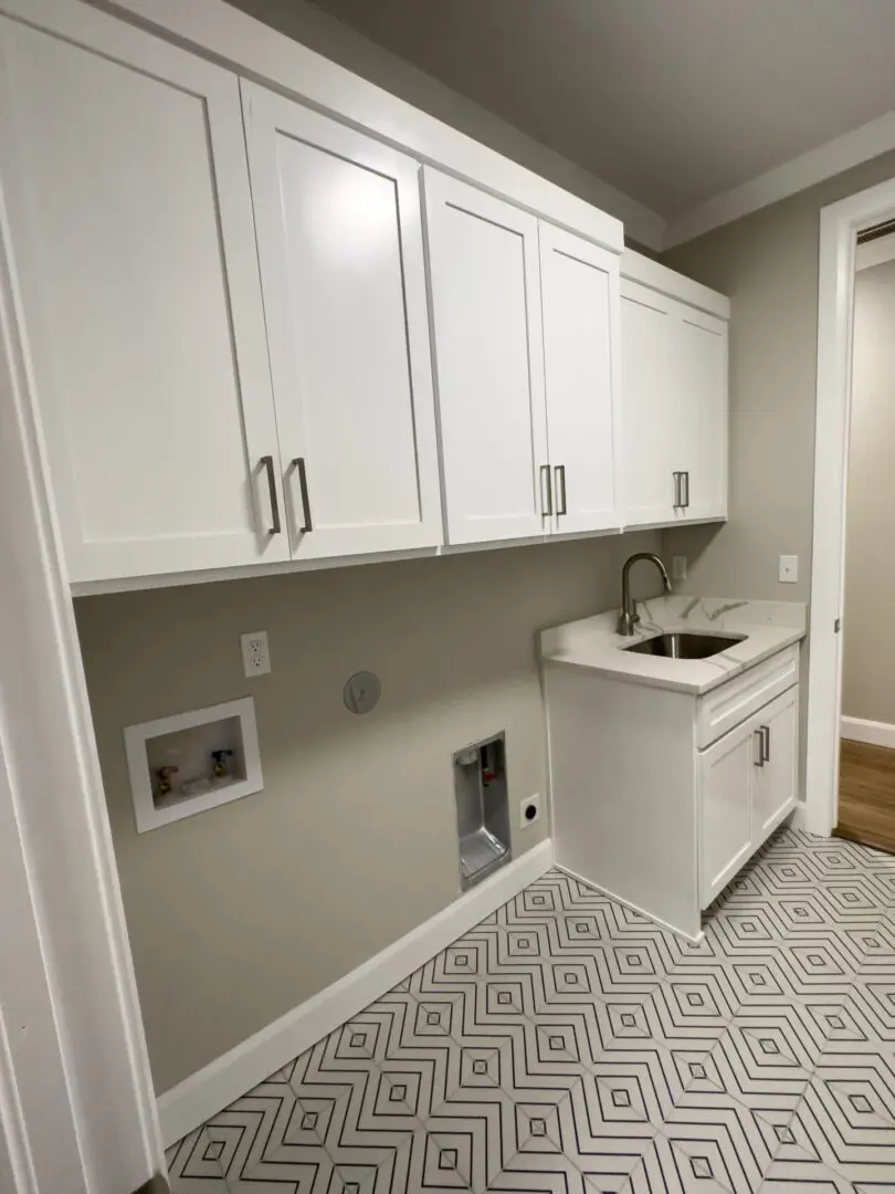 A white laundry room with cabinets and a sink.