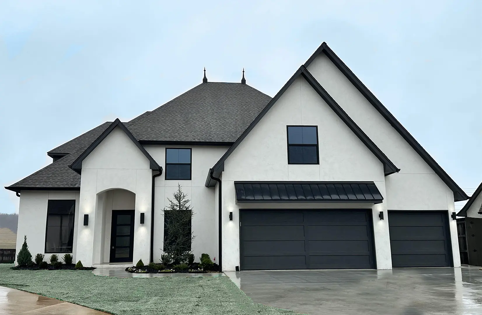 A large white house with black trim and two garage doors.