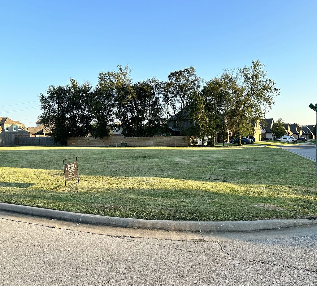 A grassy area with trees and a street sign.