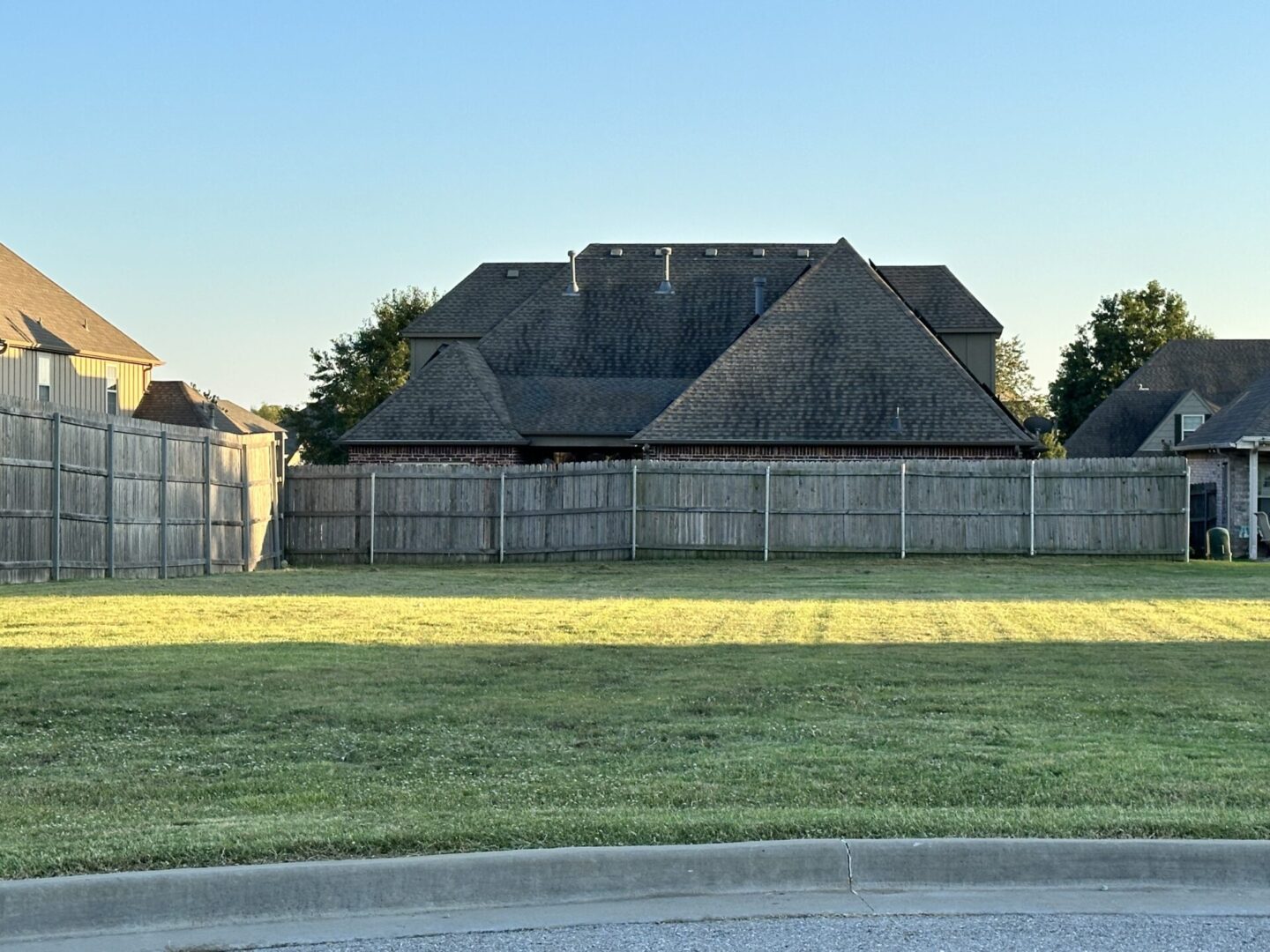 A large grassy field with a house in the background.