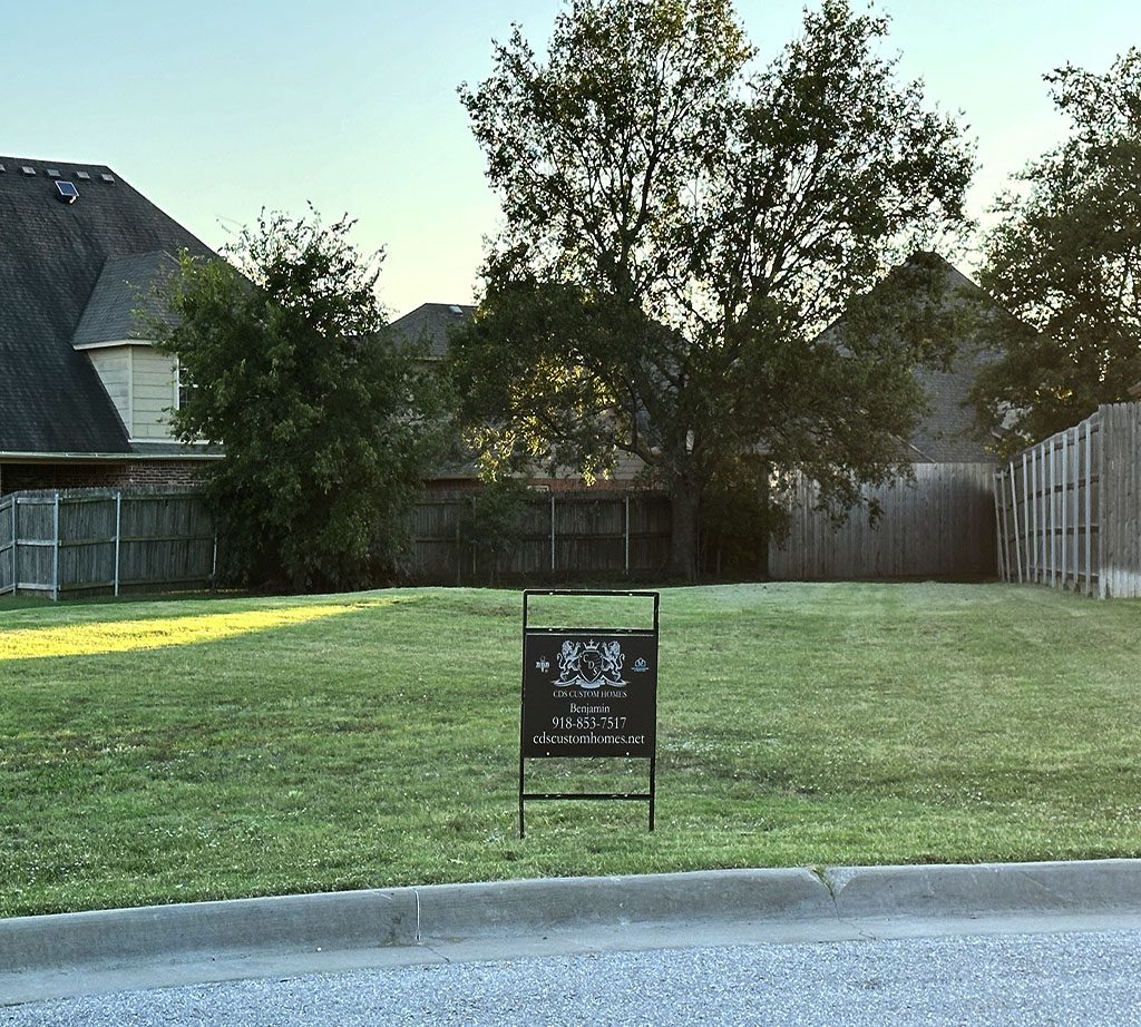 A sign in the grass near some trees